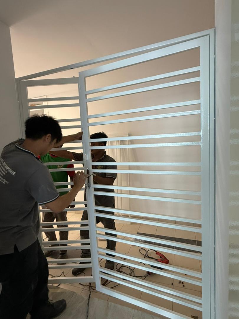 Powder-coated white horizontal-slat security gate being fitted in a Melaka home