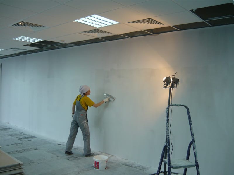 Painter skim-coating and finishing an interior wall on site