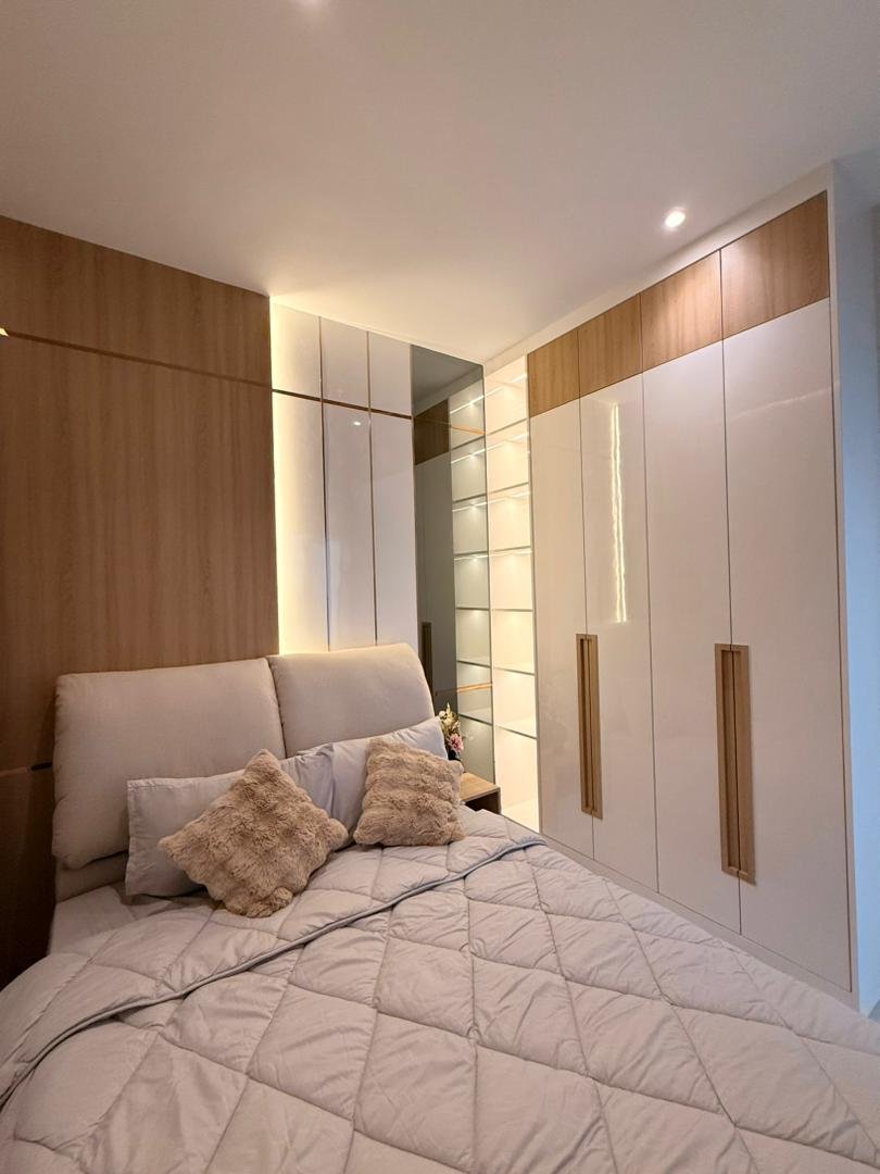 Guest bedroom with white gloss wardrobe, oak handles and lit glass display shelving, Klebang showroom